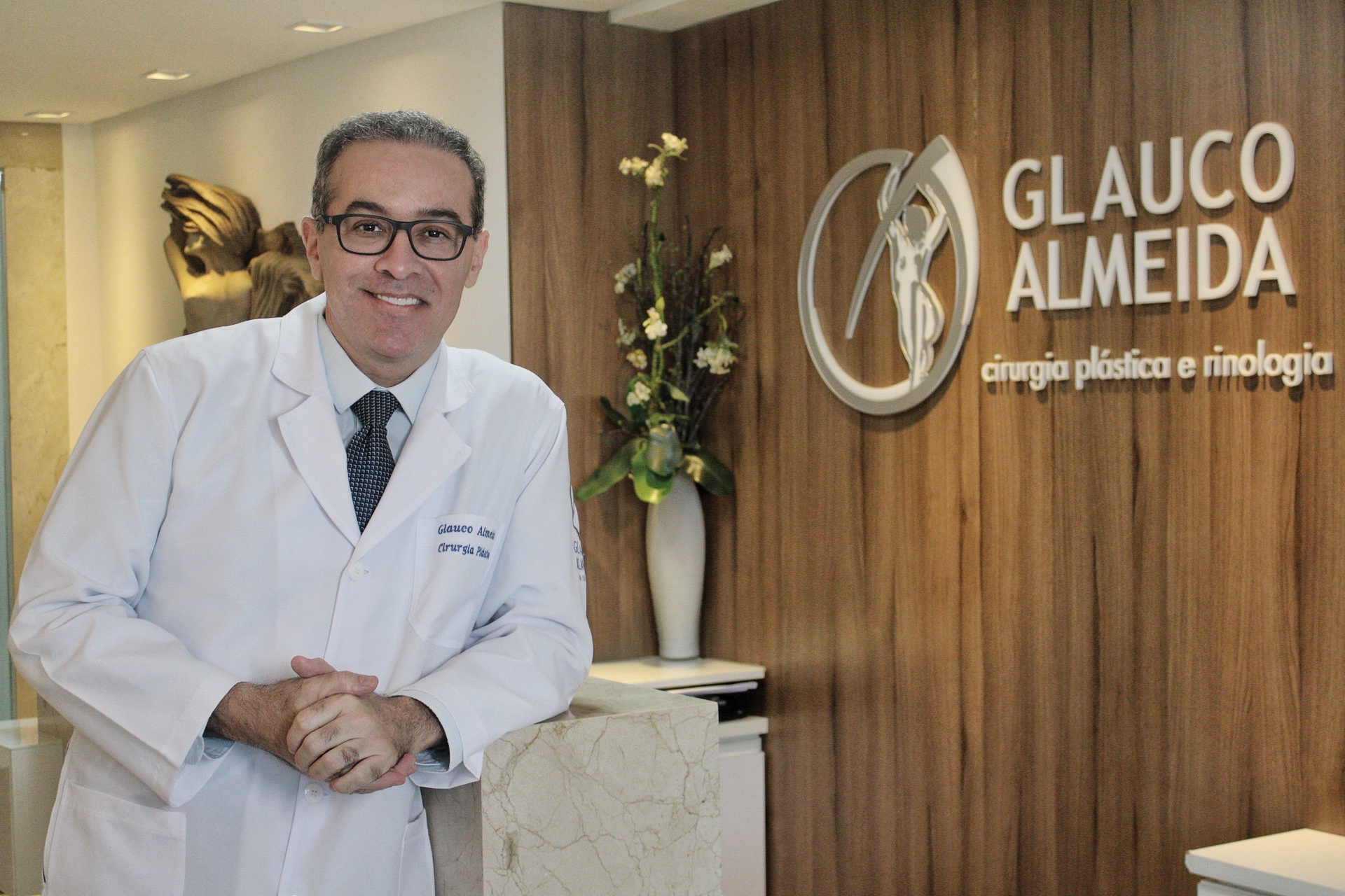 Dr. Glauco Almeida de jaleco na recepção ampla do consultório